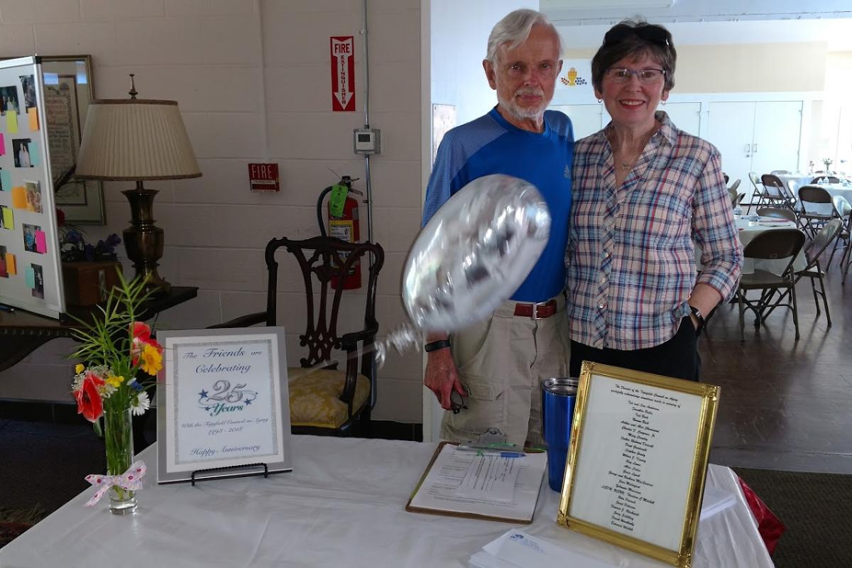 A Pair of Volunteers Pose with 25 Years of the Friends of the Topsfield COA Display