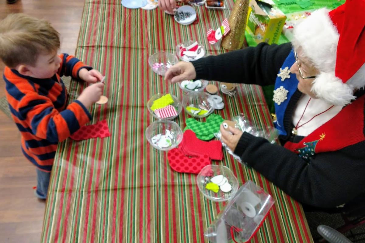Shirley Assists a Young Visitor to Santa's Workshop during the 2018 Holiday on the Green Event