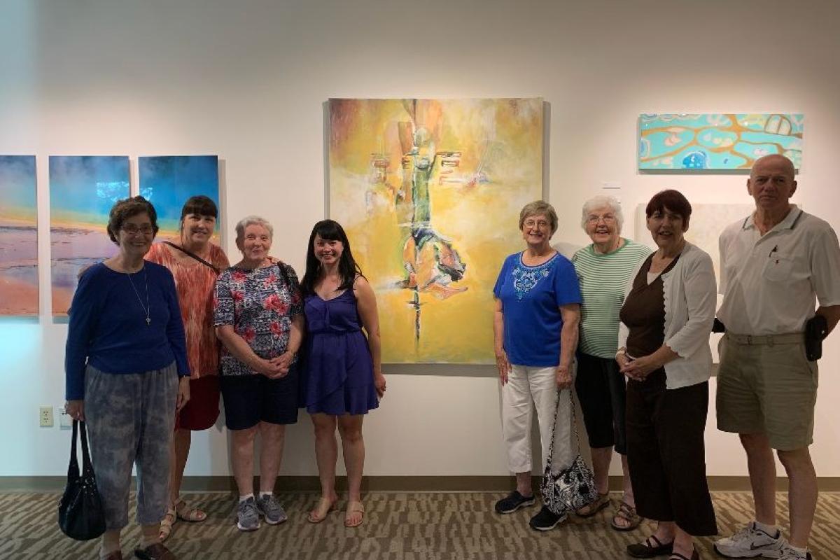 Several Guests Pose with an Artist in Front of Her Painting during a Reception at Endicott College
