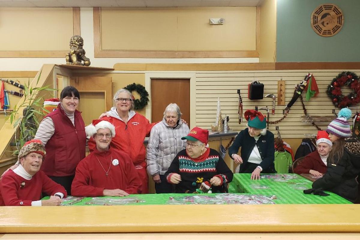 A Group of Festive Seniors Man a Craft Table during a Town-wide Holiday Celebration