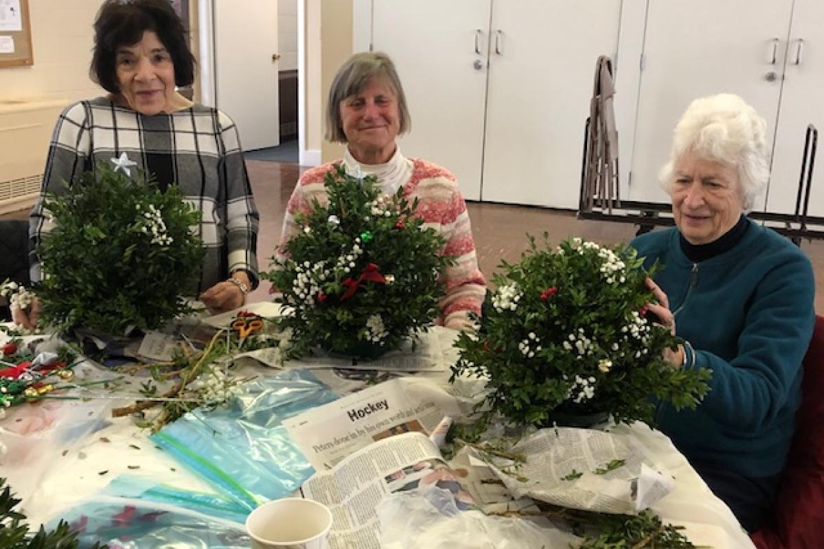 Three Women Pose with Handcrafted Boxwood Trees